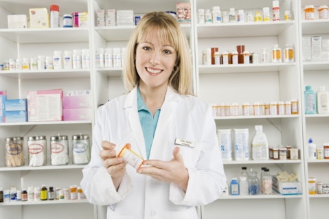pharmacist, store, shelves, drugs, chemist, profession, horizontal, adult, drugstore, one, female, medicine, health care, woman, showing, prescribing, indoors, doctor, prescribe, sell, white, medical, retail, occupation, caucasian, smile, holding, standing, person, lab coat, shop, pharmacy,
