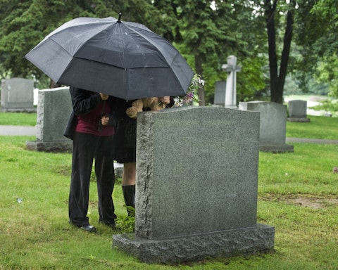 grave, umbrella, stone, rain, dead, children, bear, young, site, wet, tomb, cemetary, cemetery, flowers, trees, funeral, teddy, grass, outside, people, black, female, buried,