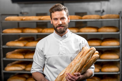 adult, baguette, bake, bakehouse, baker, bakery, baking, bread, bread baking, bun, caucasian, cheerful, chef, commercial, factory, food, fresh, gourmet, handsome, happy, indoors, industrial, industry, job, male, man, manufacture, manufacturing, model, occupation, person, portrait, production, profession, professional, rows, shelves, shop, smiling, standing, tasty, uniform, worker, working, workplace
