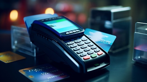 A close-up of a modern payments terminal with a pile of credit cards on the side.
