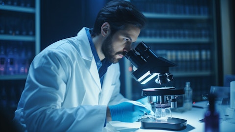 A healthcare professional in a lab coat holding a microscope and looking at a slide under the lens.