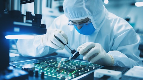 A technician in a clean room assembling a semiconductor chip using a microscope.