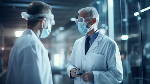 A team of healthcare professionals in lab coats and masks meeting at a hospital ward.