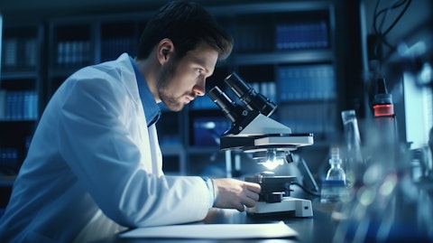 A researcher in a lab with a microscope examining a sample.