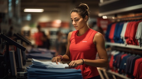 A store employee in an athletic apparel store restocking merchandise.