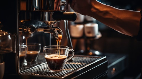 A barista pouring a freshly brewed cup of coffee from a high-end espresso machine.