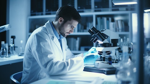 A laboratory technician in a white coat holding a microscope and examining a vial of biopharmaceuticals.
