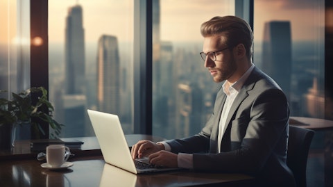 A successful portfolio manager working on a laptop in a large office with a city view, representing the success of the company in the financial sector.