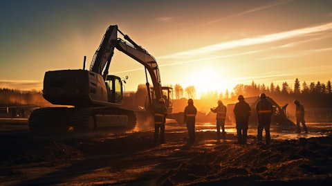 A construction crew working in the field with earthmoving equipment illuminated by a setting sun.