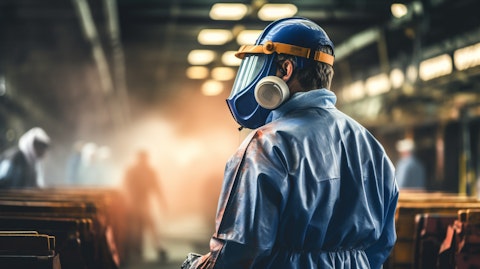 A worker in a paint manufacturing plant wearing a protective suit and mask.