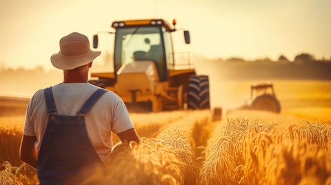 A farmer in overalls, harvesting a golden cornfield with a tractor in the background.