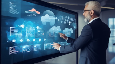 An executive in suit presenting a large touch screen of the company's cloud-based enterprise platform.