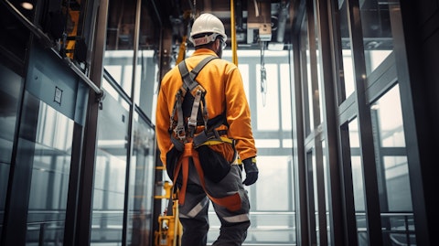 A technician in a safety harness inspecting a passenger elevator in a modern office building.