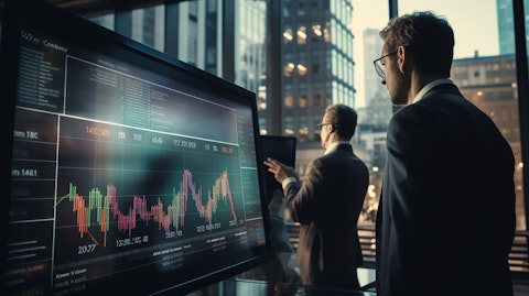 A wide angle shot of a team of bankers and financial advisors evaluating an investment portfolio on a touchscreen monitor.