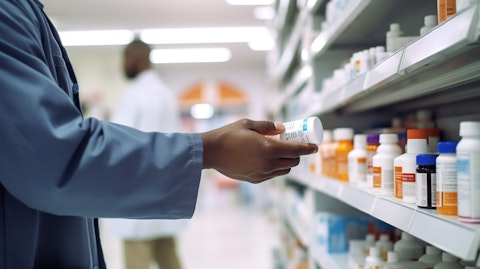 A pharmacist handing someone a prescription bottle containing the company's biopharmaceutical product.