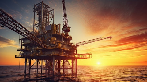A close-up view of an oil rig, its structure illuminated against the setting sun.