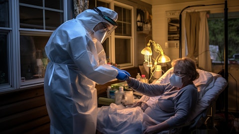 A home infusion nurse in full PPE gown delivering treatments to a patient in their own home.