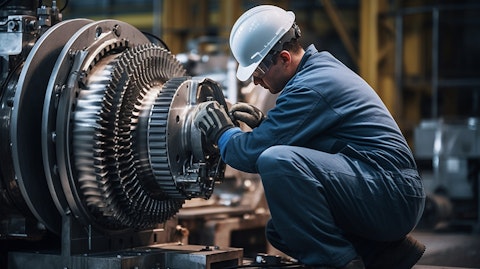 A technician in protective gear repairing a huge generator at a power plant.