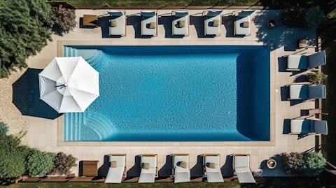 Aerial view of a swimming pool with outdoor furniture surrounding it. 