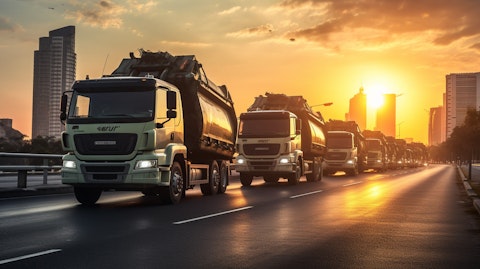 A fleet of waste management trucks driving through a city at sunrise.