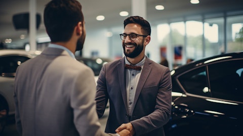 A happy customer inspecting a newly purchased used car with the help of a sales assistant.