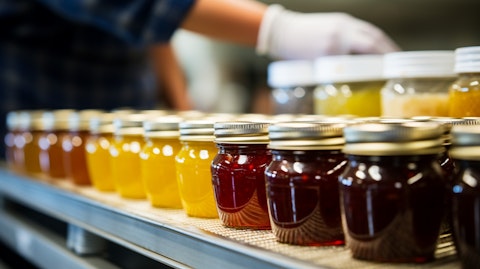 A closeup of an assembly line worker inspecting a newly produced jar of condiments and sauces.