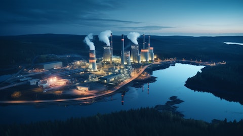 Aerial view of a power plant near a lake lit up at night, showing off the company's expansive electricity generation capabilities.