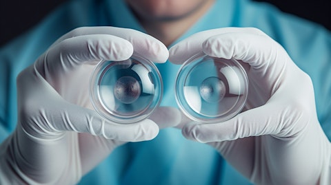 A doctor wearing gloves and a mask holding a pair of contact lenses in their hand.
