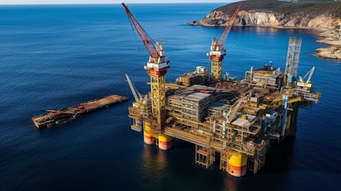 An aerial view of an oil rig with drillers in hard hats working on the platform.