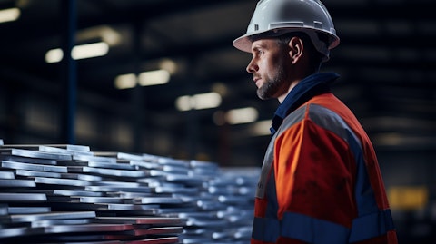 A close-up of a worker inspecting a galvanised sheet steel product in a well-lit warehouse.