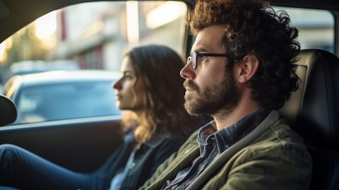 A ridesharing passenger and driver in a car, looking out the window in anticipation of their destination.