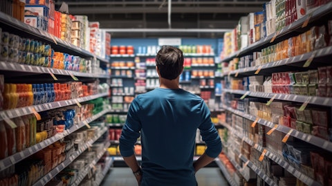 A shopper browsing through a discount retailers merchandise aisle filled with a wide variety of items.