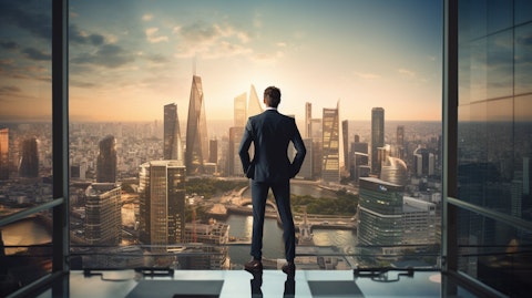 A businessperson looking out a city skyline, from the top floor of a high-rise building.