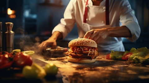 A chef in a kitchen preparing a fast food meal of chicken, pizza and burgers.