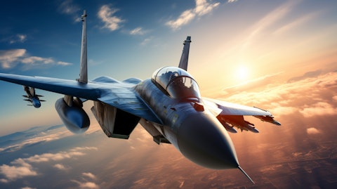 A military jetfighter against a deep blue sky with the sun behind it.