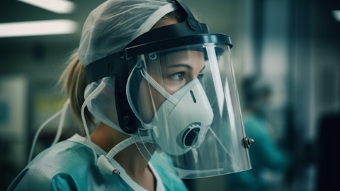 A healthcare professional in a protective mask and headgear adjusting a ventilation device.