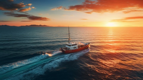 An aerial view of a boat sailing in the open sea at sunset.