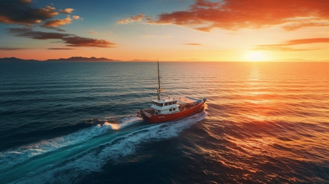 An aerial view of a boat sailing in the open sea at sunset.