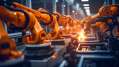A row of robotic arms in a factory, assembling semiconductor products.