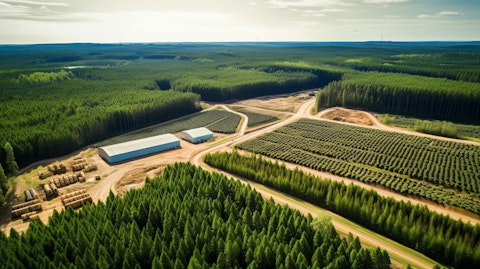 A wide shot of lush green forestry surrounding a timber harvesting facility.