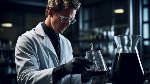 A laboratory scientist in a lab coat examining a beaker of high purity carbon black.