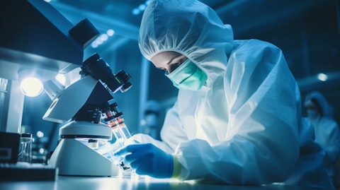 A lab technician using a microscope to examine the biopharmaceutical company's molecules.