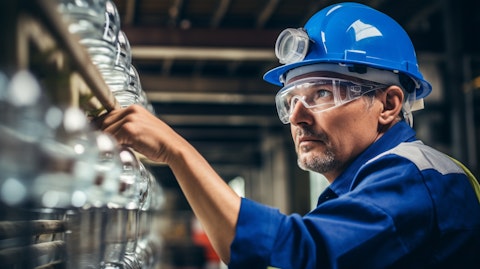 A factory worker with protective goggles and a hardhat inspecting a water filtration system.