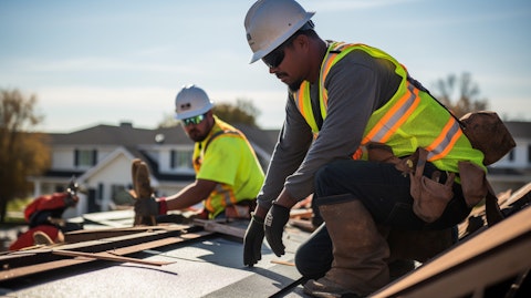 A team of construction workers installing a roof with asphalt shingles.