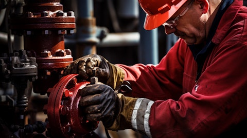A close up of a worker tightening a valve on an oil rig.