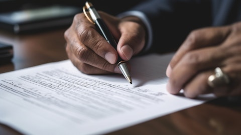 Close up of a person's hand signing a life insurance policy.