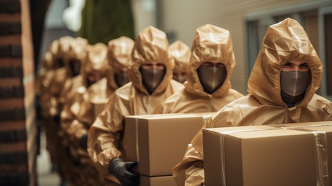 Workers in protective gear carrying packages of coated unbleached kraft for shipping.