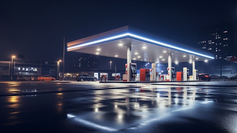 An exterior view of an illuminated gas station at night, surrounded by cars.