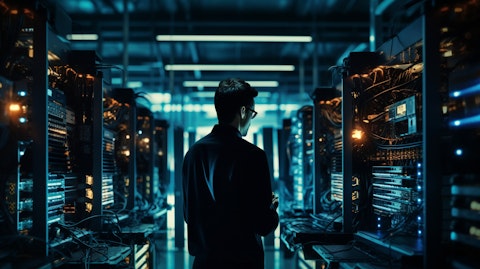An IT technician in an open office with stacks of servers in the background.