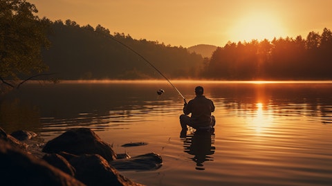 A person fishing in the lake, using the companies fishing equipment to reel in their catch.